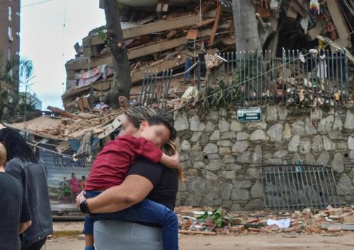 Bimbo in braccio davanti a macerie