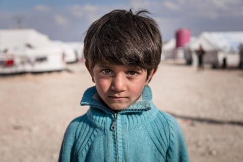 Un bambino di sette anni, accanto alla tenda della sua famiglia in un campo per rifugiati