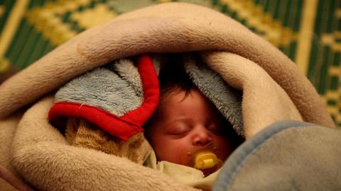 Bambina dorme avvolta tra le coperte - Save the Children 