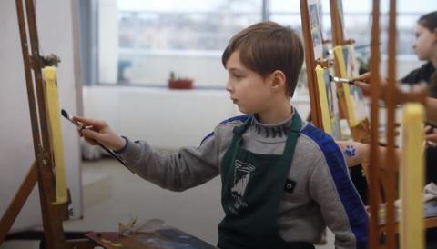 Un bambino rifugiato che dipinge in uno Spazio a Misura di Bambino