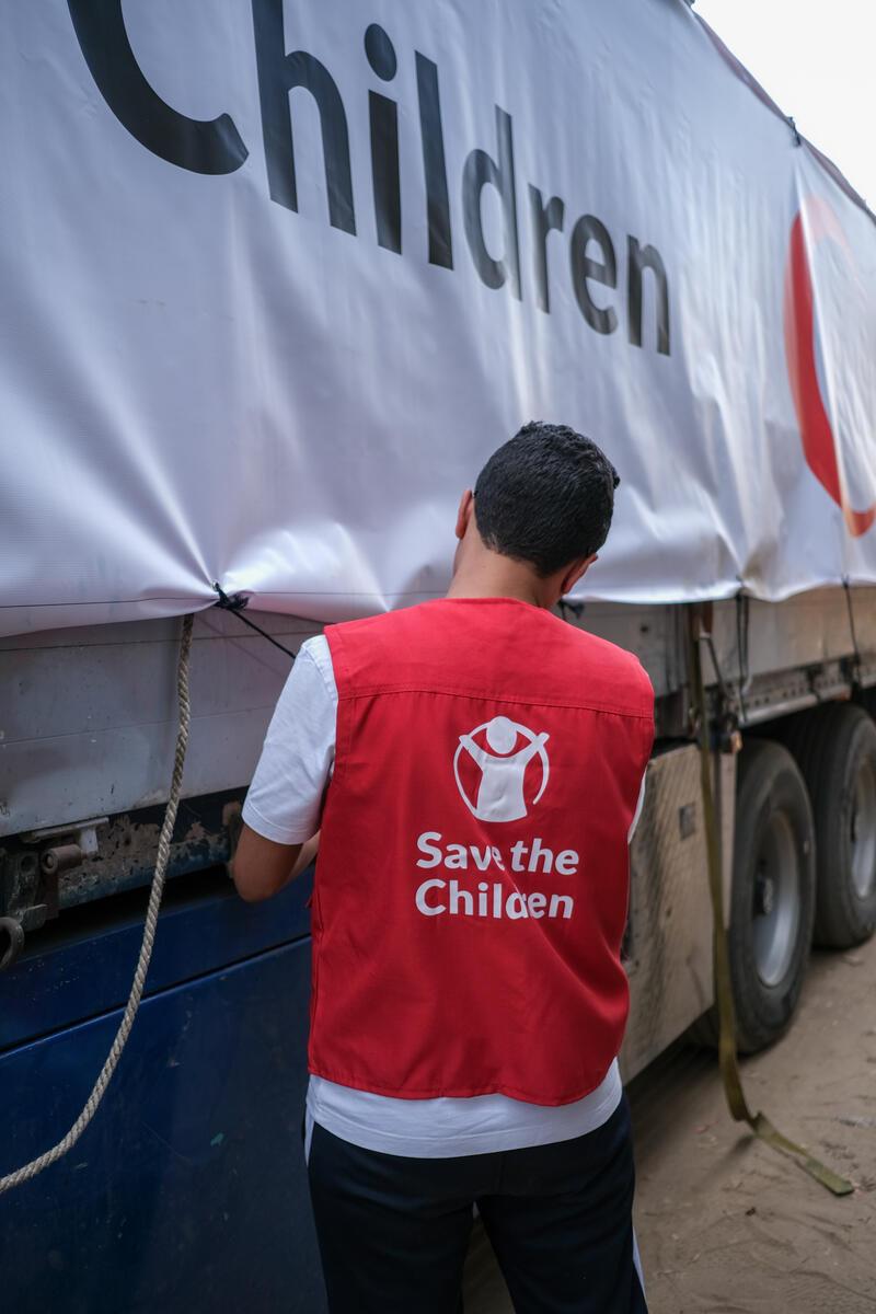 save the children staff aggiusta striscione sul camion di provviste